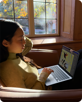 Osoba siedząca na krześle i korzystająca z MacBooka Air